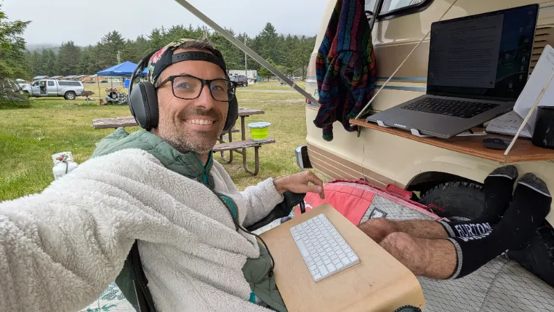 Justin working at a laptop set up outside a camper van
